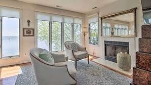 A living room with a fireplace, a large mirror, and a view of the outdoors. - Luxe Chesapeake Bay Getaway < 20 Mi to Annapolis! (Shady Side)
