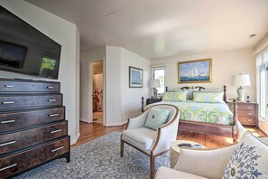 Ein Schlafzimmer mit Bett, Sessel, Kommode und Fernseher.