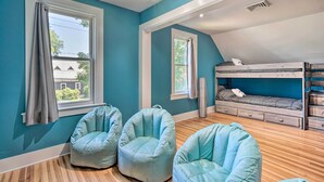 Ein Zimmer mit türkisfarbenen Wänden, Holzboden, einem Etagenbett und zwei Sitzsäcken.