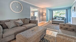 Ein Wohnzimmer mit grauem Sofa, passendem Hocker und einer runden Wanduhr.