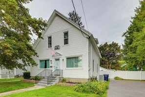 A two-story white house with a front porch, a flag, and a mailbox. - Downtown Retreat w/ Grill, Fire Pit & Wet Bar (Lake George)
