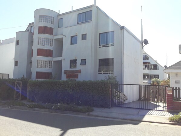A multi-story residential building with a modern architectural design, featuring balconies and a gated entrance. - Habitamar Maitencillo (Puchuncavi)