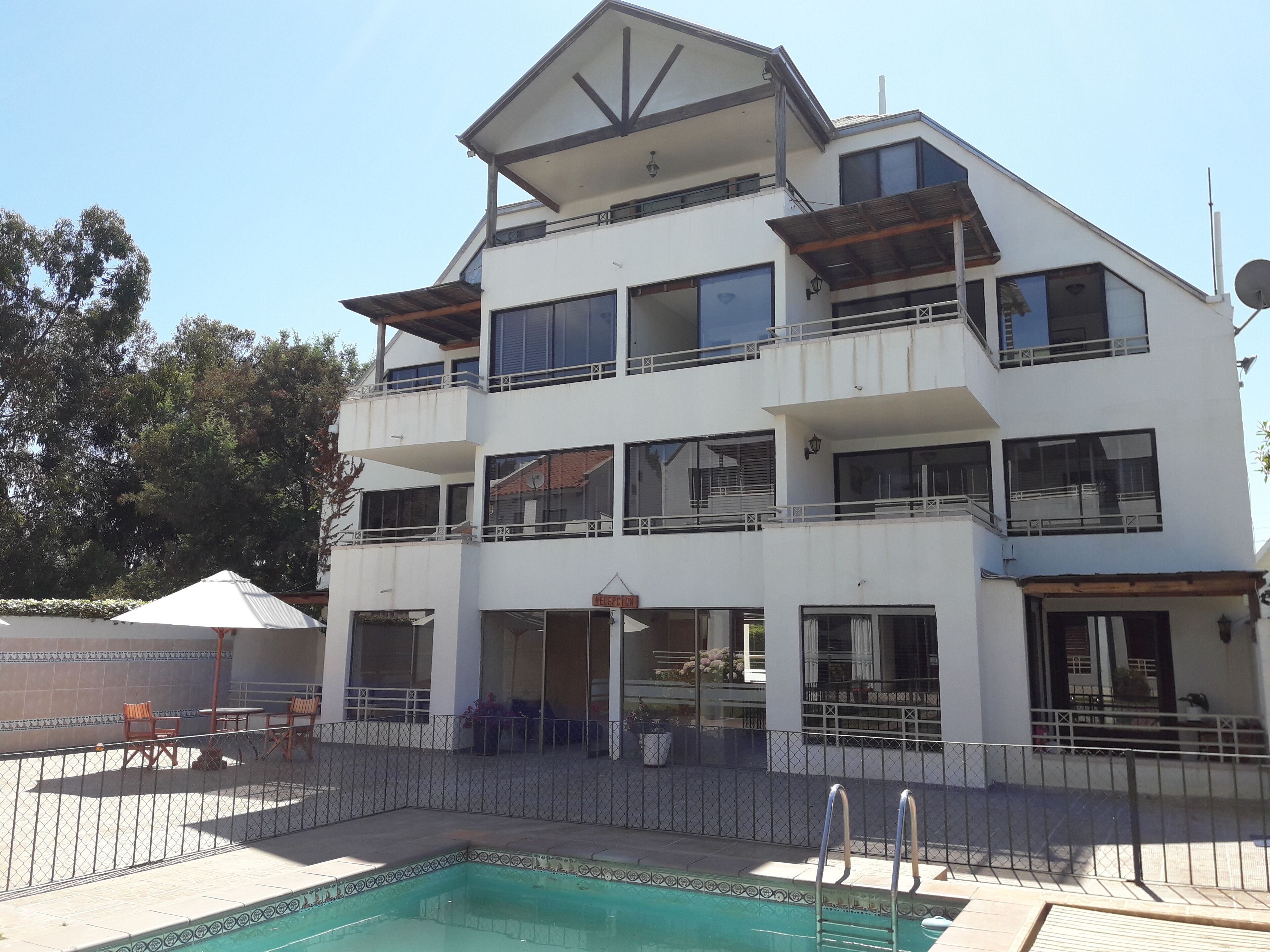 A multi-story hotel with a pool area, including a reception desk and outdoor seating.
