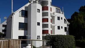 A modern multi-story building with a white exterior, multiple windows, and satellite dishes. - Habitamar Maitencillo (Puchuncavi)