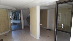 A hallway with a glass door, beige walls, and tiled flooring. - Habitamar Maitencillo (Puchuncavi)