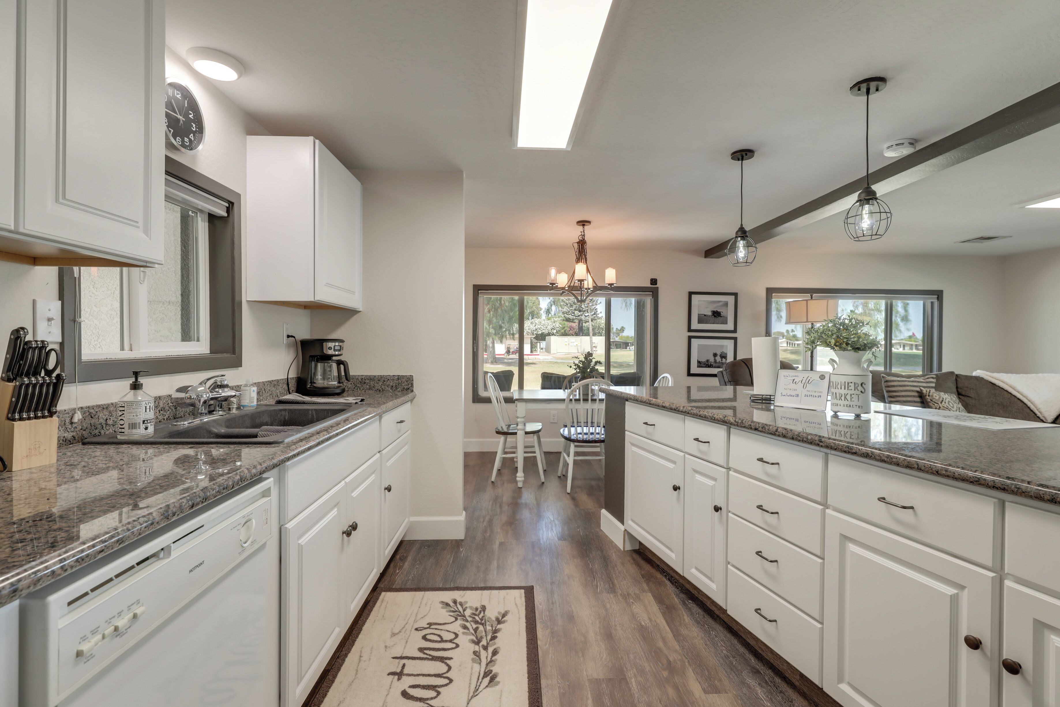 Una cocina moderna con armarios blancos, encimeras de granito y una isla central.