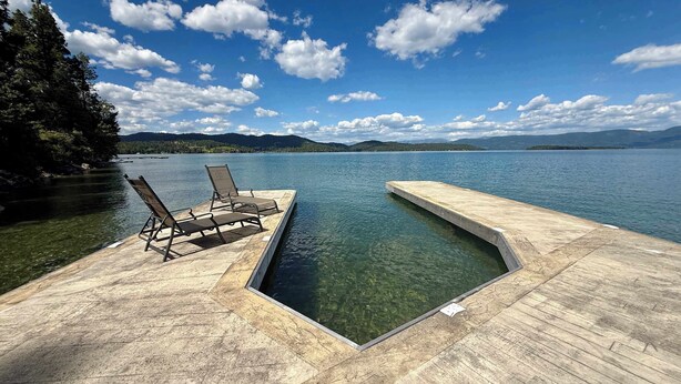 Ein klares Schwimmbecken mit Holzterrasse und Liegestühlen.