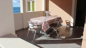 A balcony with a table and chairs, a window with a view of the sea, and a door. - Apartment in Sevid with Seaview, Balcony, Air condition, WIFI (5169-2) (Sevid)