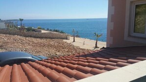 A coastal view with a tiled roof, a sandy beach, and the sea in the background. - Apartment in Sevid with Seaview, Balcony, Air condition, WIFI (5169-2) (Sevid)