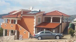 A two-story house with a red-tiled roof, a car parked in front, and a satellite dish on the roof. - Apartment in Sevid with Seaview, Balcony, Air condition, WIFI (5169-2) (Sevid)