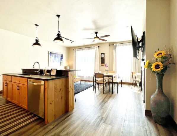 Open concept living area with full kitchen, dining area, living room area, office space, TV and gas fireplace - Mural Place, Cool Downtown Condo (Columbia Falls)