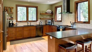 Una cocina moderna con armarios de madera, una isla central y ventanas amplias.