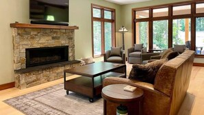 Una sala de estar con chimenea de piedra, televisor de pantalla plana, sofá y una mesa de centro.