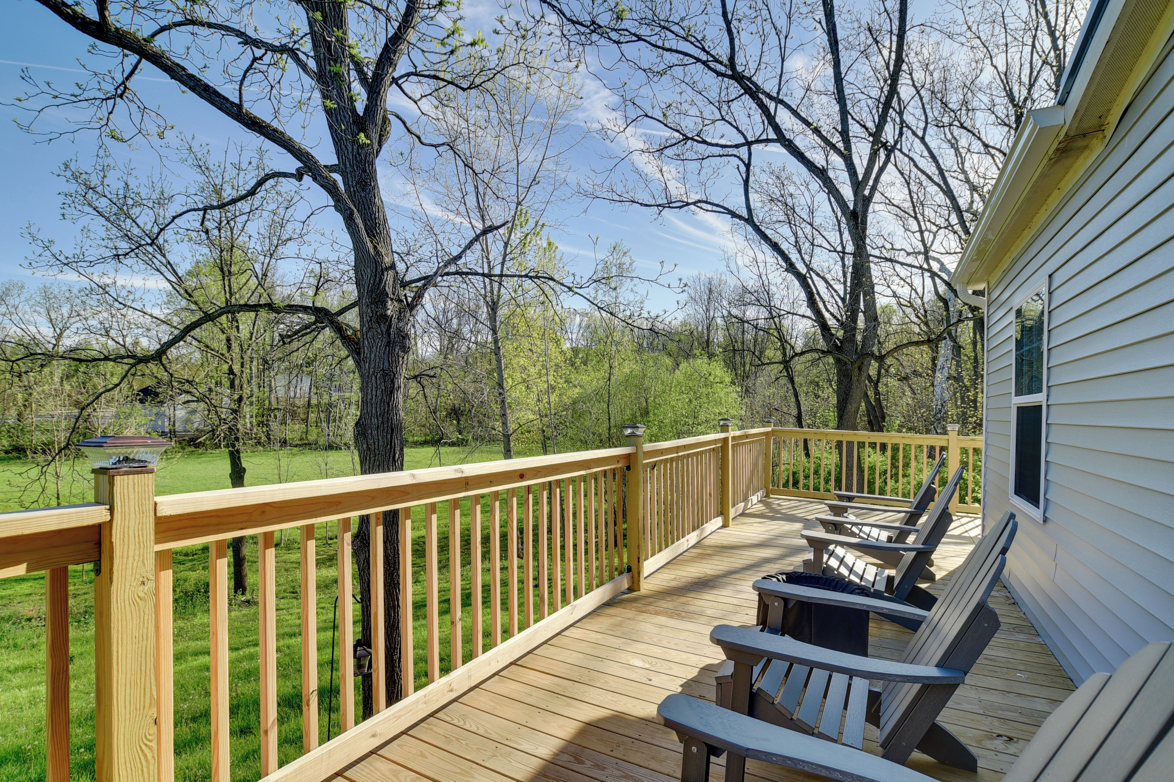 A wooden deck with outdoor seating and a view of a grassy area and trees.