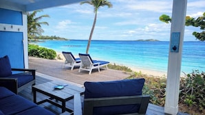 A covered outdoor seating area with a view of the ocean and a palm tree. - Bella Vista Breeze - Beachfront Oasis awaits your arrival. (George Town)