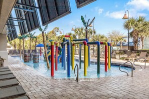 Relax by the pool surrounded by lounge chairs and umbrellas, with a play area for kids nearby.