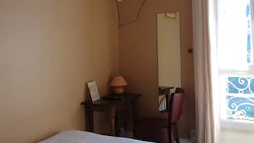 A hotel room with a bed, a desk, a chair, a television mounted on the wall, a window with curtains, and a painting on the wall.