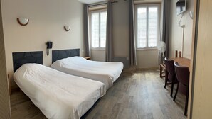 Une chambre d’hôtel avec deux lits, un bureau et une chaise.
