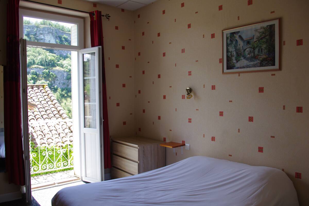 Un dormitorio con una cama, un aparador, una ventana con cortinas y un cuadro en la pared.