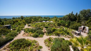 A garden with a fountain, seating area, and a view of the sea.