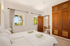 Ein Schlafzimmer mit zwei Betten, einem Holzschrank und Blick auf Grünflächen.