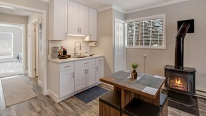 Une cuisine moderne avec des meubles blancs, une cuisinière encastrée et un coin repas comprenant une table et un banc.