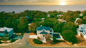 A coastal residential area with houses, a clear sky, and a sunset over the water. - Beach House (Corolla)