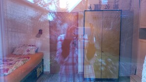 Ein Zimmer mit einem Bett, einem Kleiderschrank und einem Spiegel, der den Innenraum zeigt.