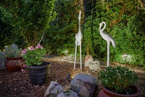 A garden with potted plants, rocks, and two bird sculptures.