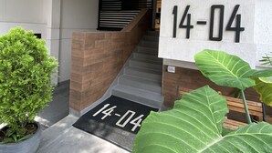 A modern building entrance with a staircase, a reception desk, and a potted plant. - Hotel 14-04 (Cali)