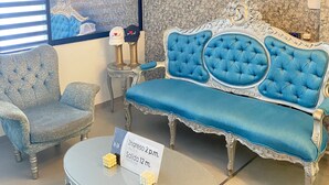 A room with a blue sofa, a matching armchair, a round table with a sign, and a patterned wall. - Hotel 14-04 (Cali)