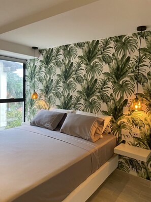 A modern bedroom with a bed, a nightstand, and a wall with a tropical leaf pattern. - Hotel 14-04 (Cali)