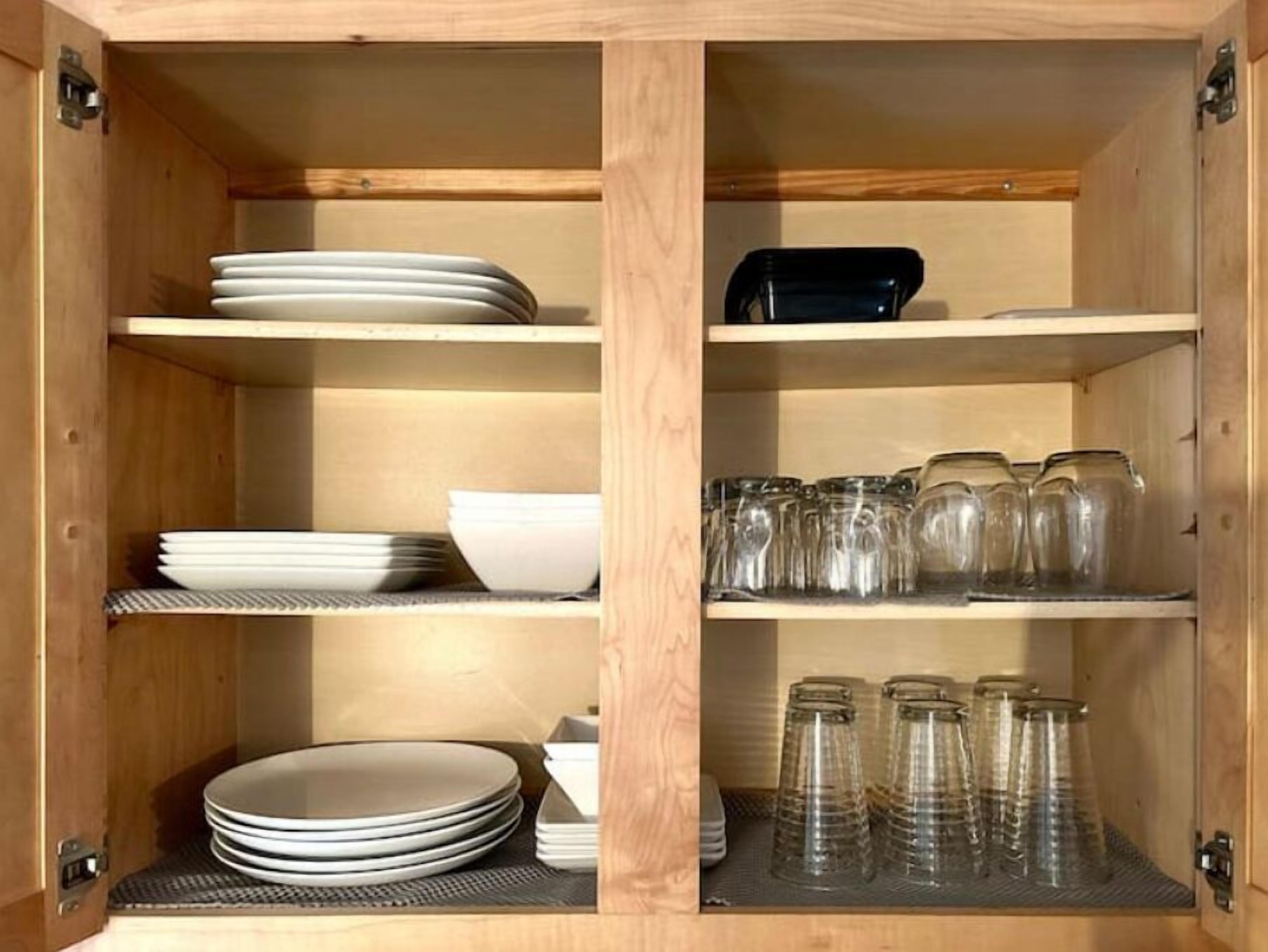 A wooden cabinet with shelves holding plates, bowls, and glass jars.