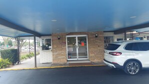A covered parking area with a white SUV parked inside. - HOTEL BLUE (DeLand)