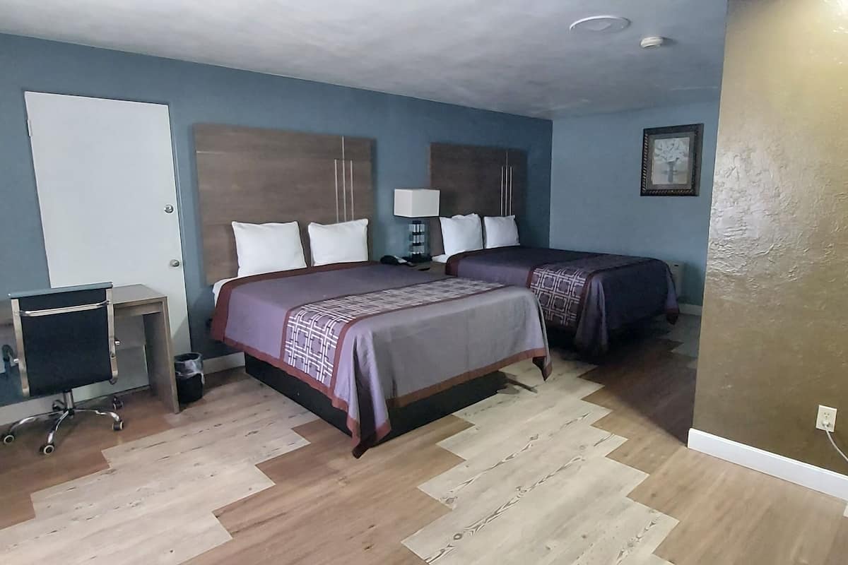 A hotel room with a bed, bedside table, lamp, and a refrigerator.