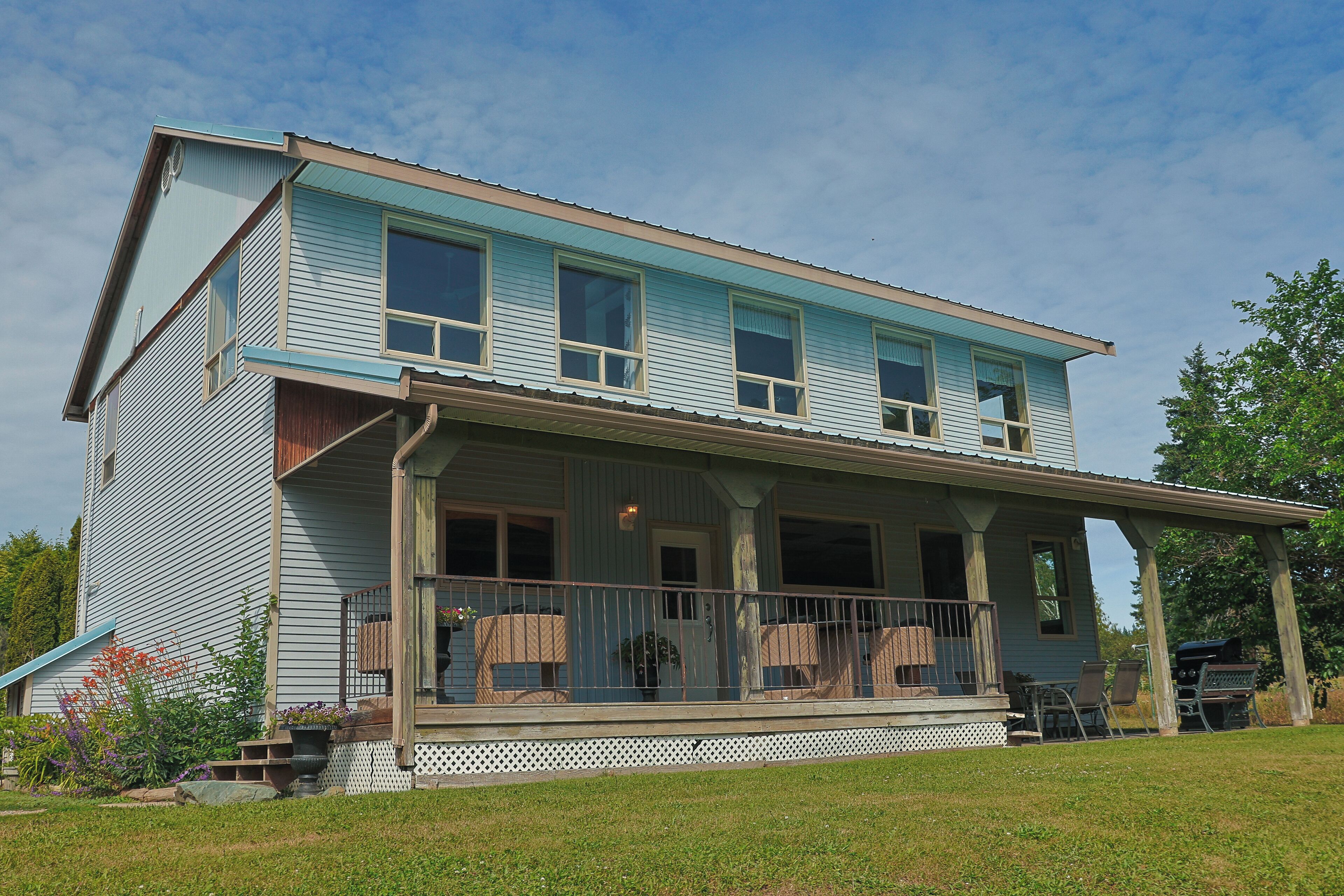 A two-story house with a porch, a covered area, and a small garden.