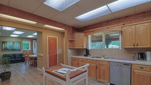 Una cocina con armarios de madera, lavavajillas y un comedor con mesa y sillas.