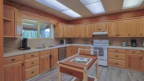 Una cocina con armarios de madera, una encimera, un fregadero, una estufa y una ventana.