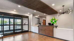 A reception area with a wooden reception desk, a modern ceiling design, and a large window with a view of the parking lot. - Extended Stay America Premier Suites - Boise - Meridian (Meridian)