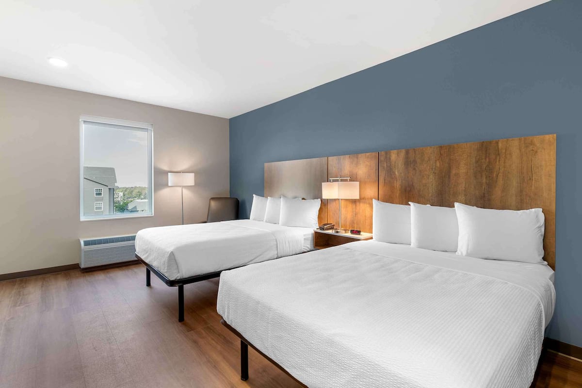 A hotel room with two beds, a large window, and a view of the outside.