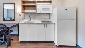 A compact kitchen with white cabinets, a microwave, a refrigerator, a sink, and a chair. - Extended Stay America Premier Suites - Boise - Meridian (Meridian)