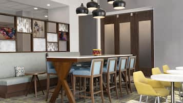 Een moderne bar met een houten bar en blauwe, beklede barkrukken, verlicht met hangende zwarte lampen.
