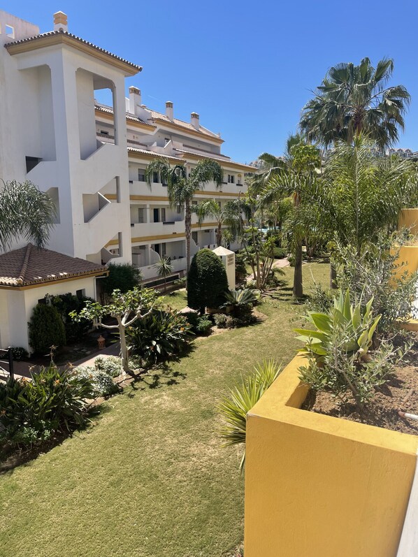 A multi-story building with balconies, surrounded by well-maintained gardens and palm trees. - Calanova Golf Sensations Outdoor Vacations (Mijas Costa)