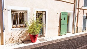 Un bâtiment devant lequel se trouve une fenêtre ornée d’une grille métallique et sur laquelle est posée une plante en pot.