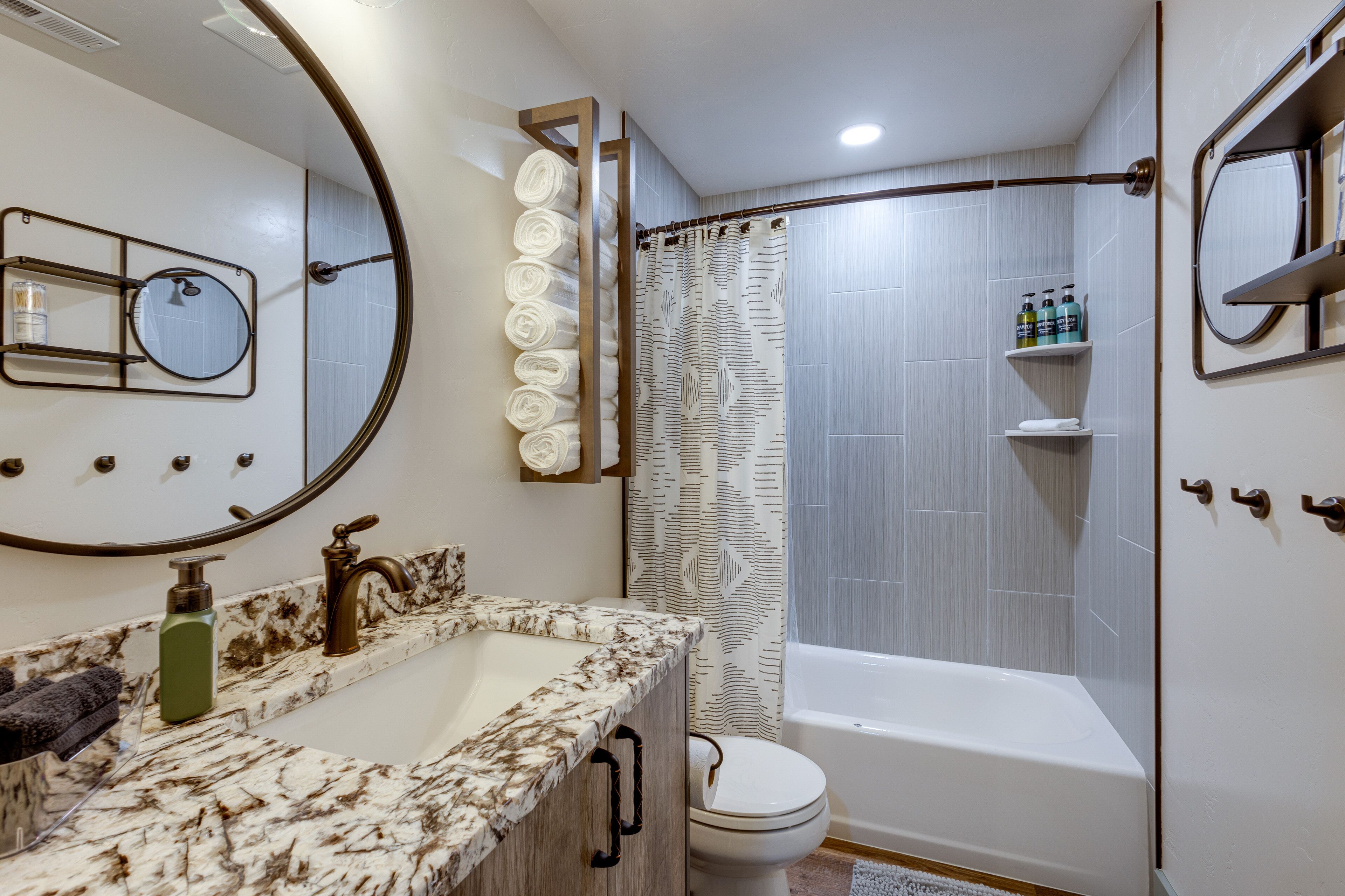 A bathroom with a marble sink, a toilet, a bathtub, and a shower curtain.