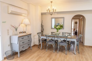 A dining area with a table, chairs, a chandelier, a mirror, and a dresser.