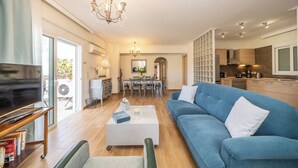 Una sala de estar moderna con televisor, sofá, mesa de centro y comedor.