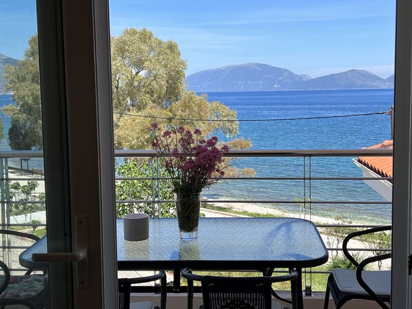 A balcony with a table, chairs, and a vase of flowers.