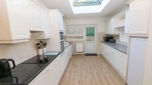 A modern kitchen with white cabinetry, a black countertop, and a skylight.