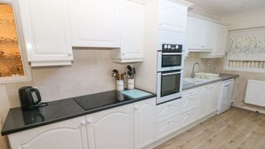 A modern kitchen with white cabinetry, a black countertop, and a double oven.